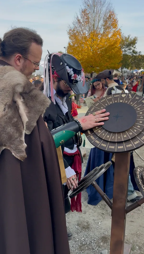 Costumed participants working a cipher wheel puzzle station on a sunny autumn day