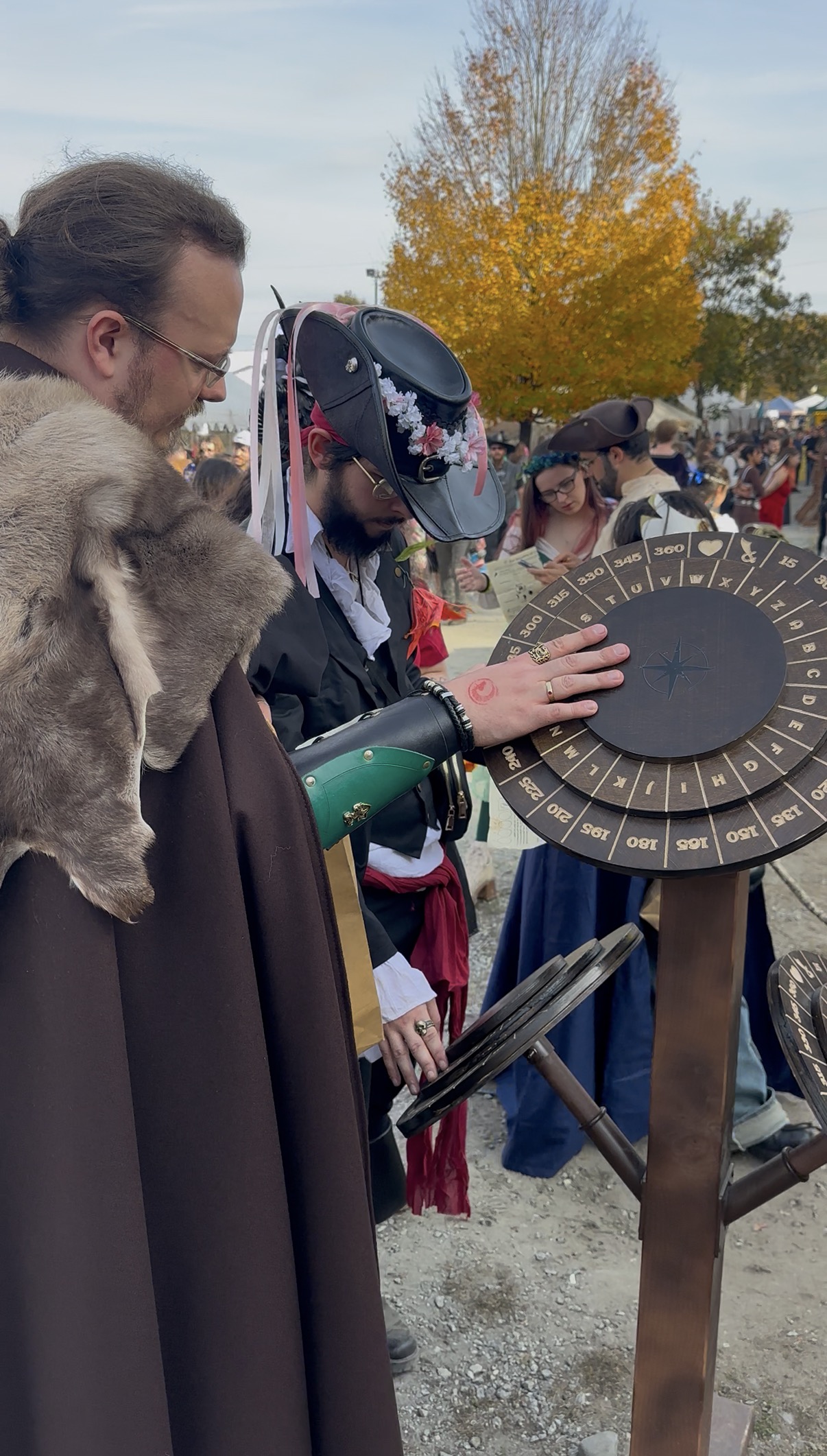 Costumed participants working a cipher wheel puzzle station on a sunny autumn day