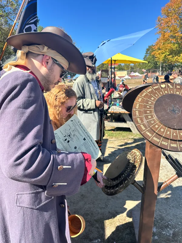 Couple in Renaissance attire working together on the cipher wheel puzzle