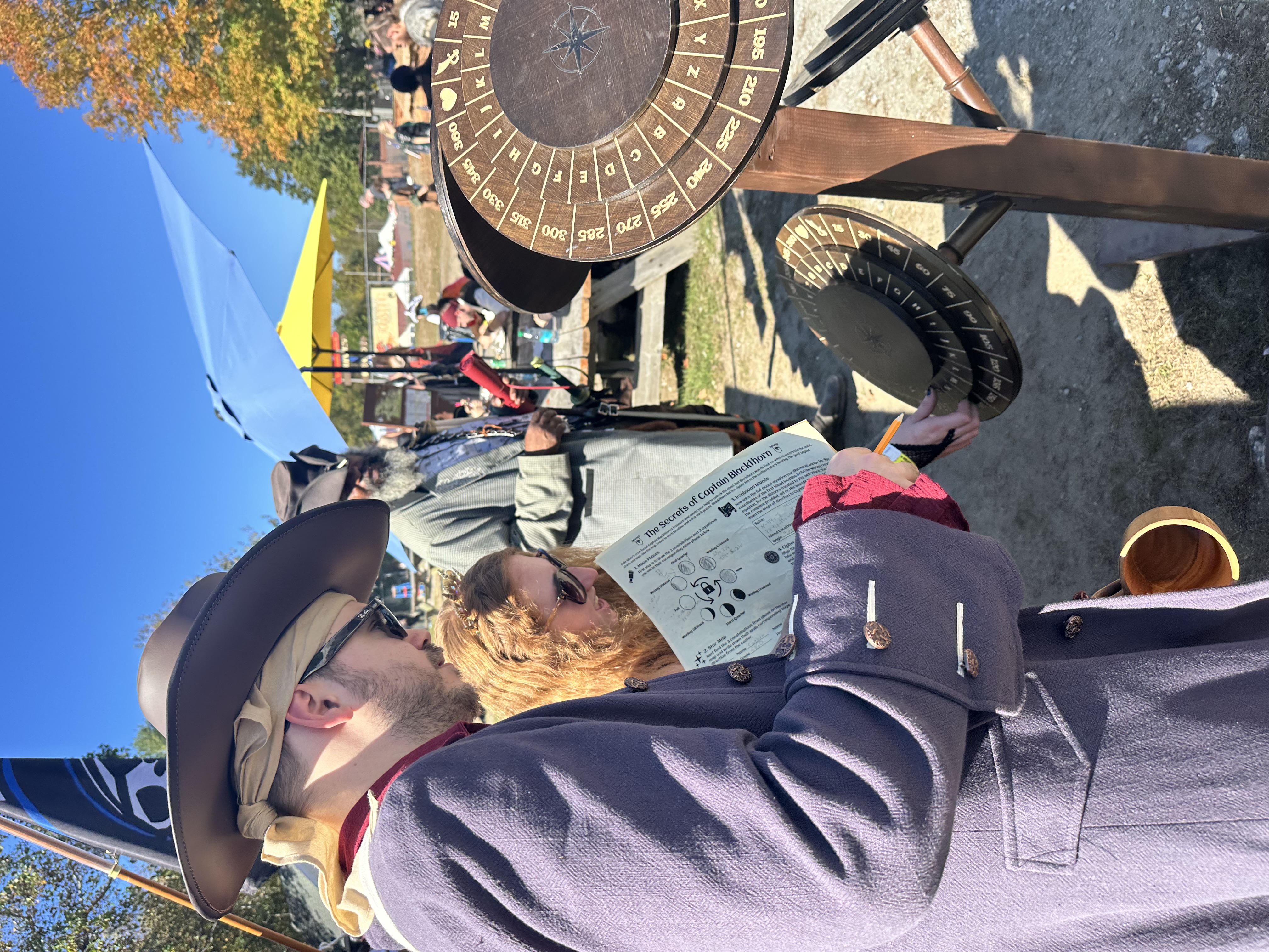 Couple in Renaissance attire working together on the cipher wheel puzzle