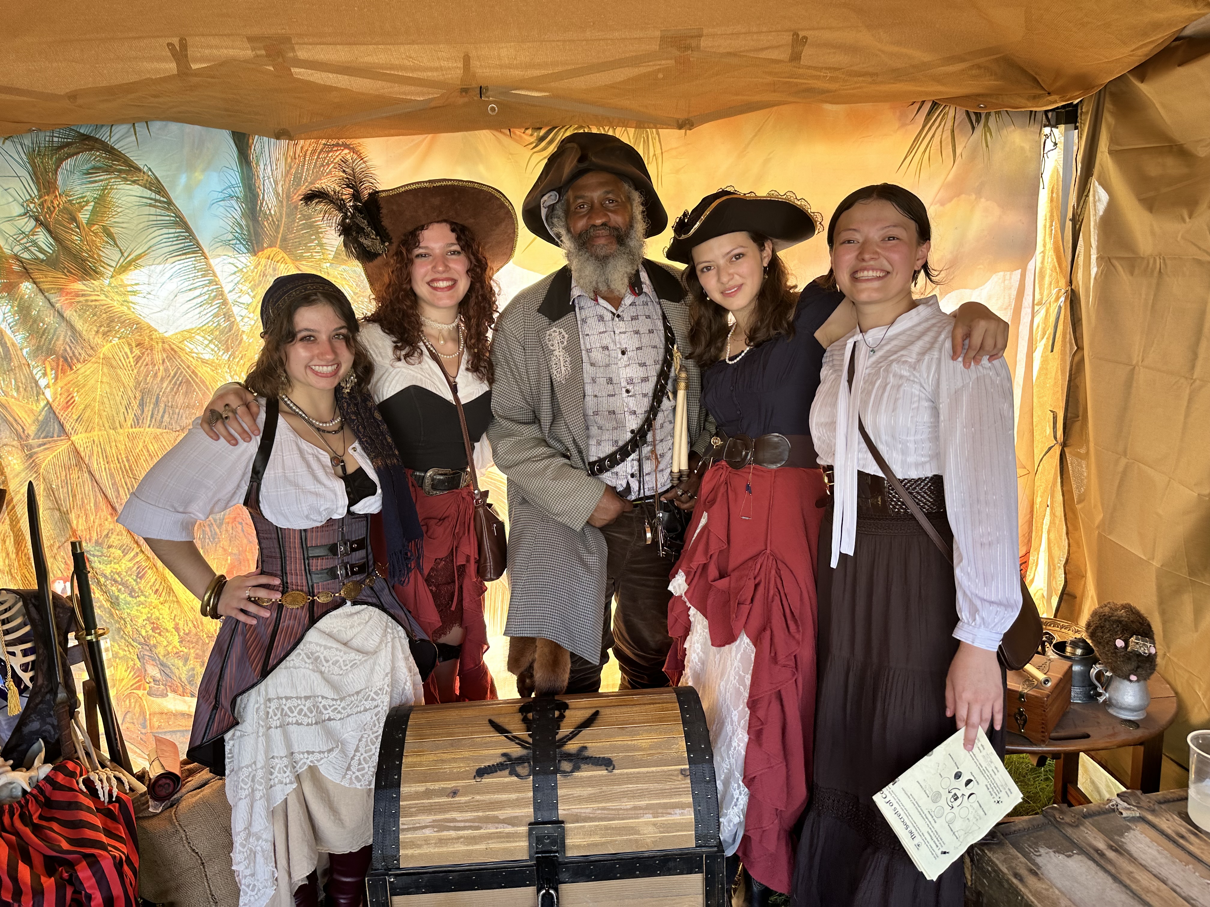 Group of pirates posing with the captain around the treasure chest