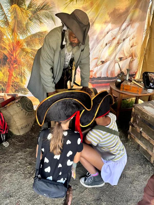 Two young children in pirate hats peering into the treasure chest