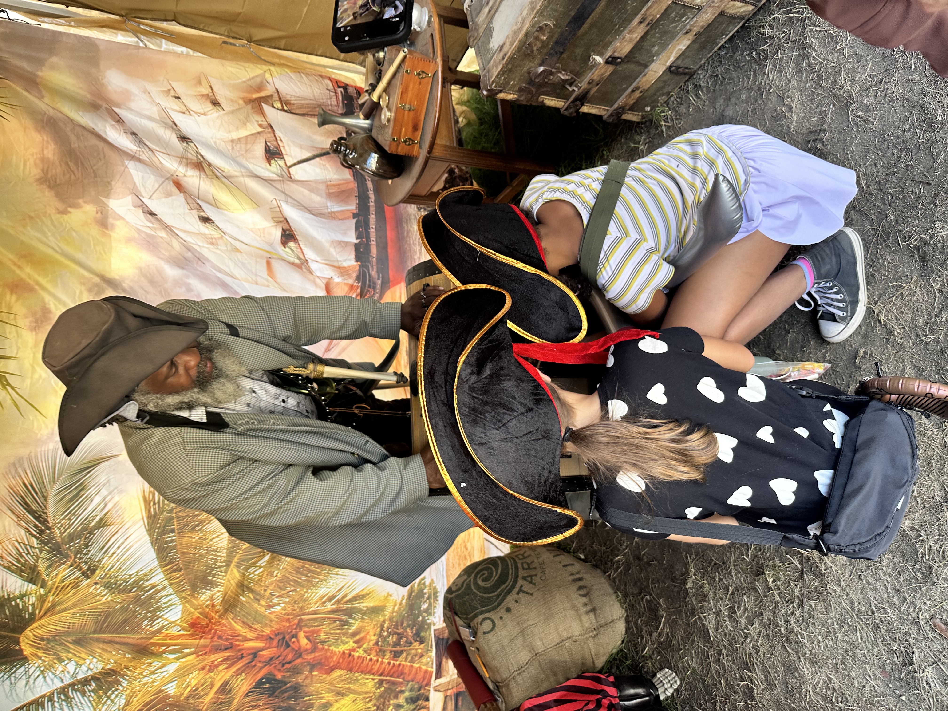 Two young children in pirate hats peering into the treasure chest