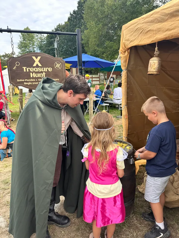 Children working to unlock a padlocked treasure barrel filled with gold coins