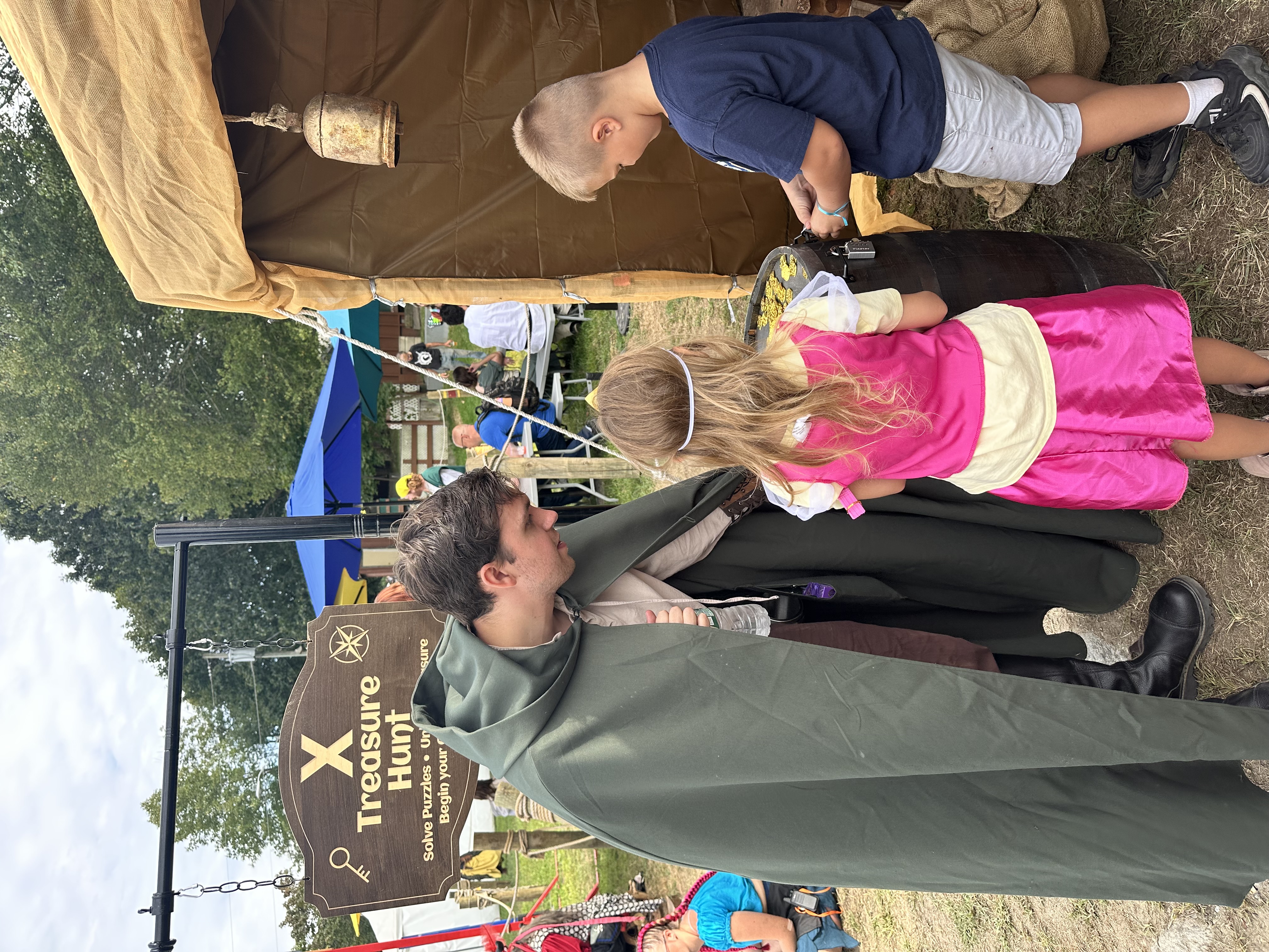 Children working to unlock a padlocked treasure barrel filled with gold coins
