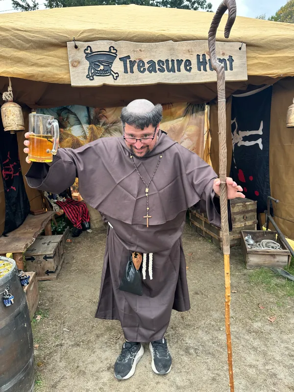 Medieval friar raising an ale mug at the X Treasure Hunt entrance
