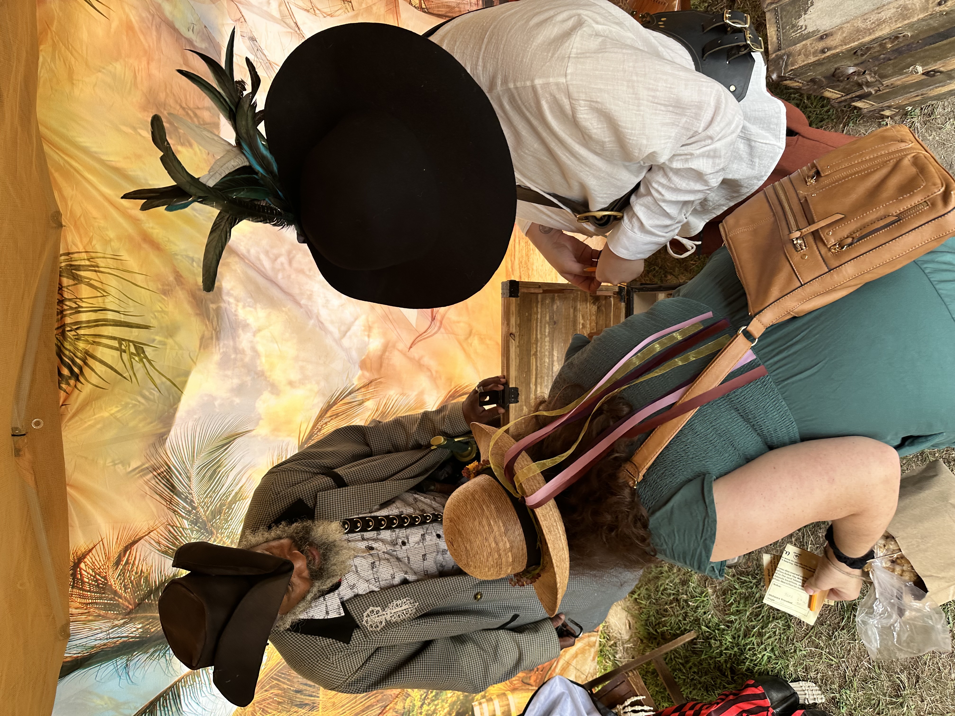 Two participants in Renaissance hats opening the treasure chest inside the pirate tent