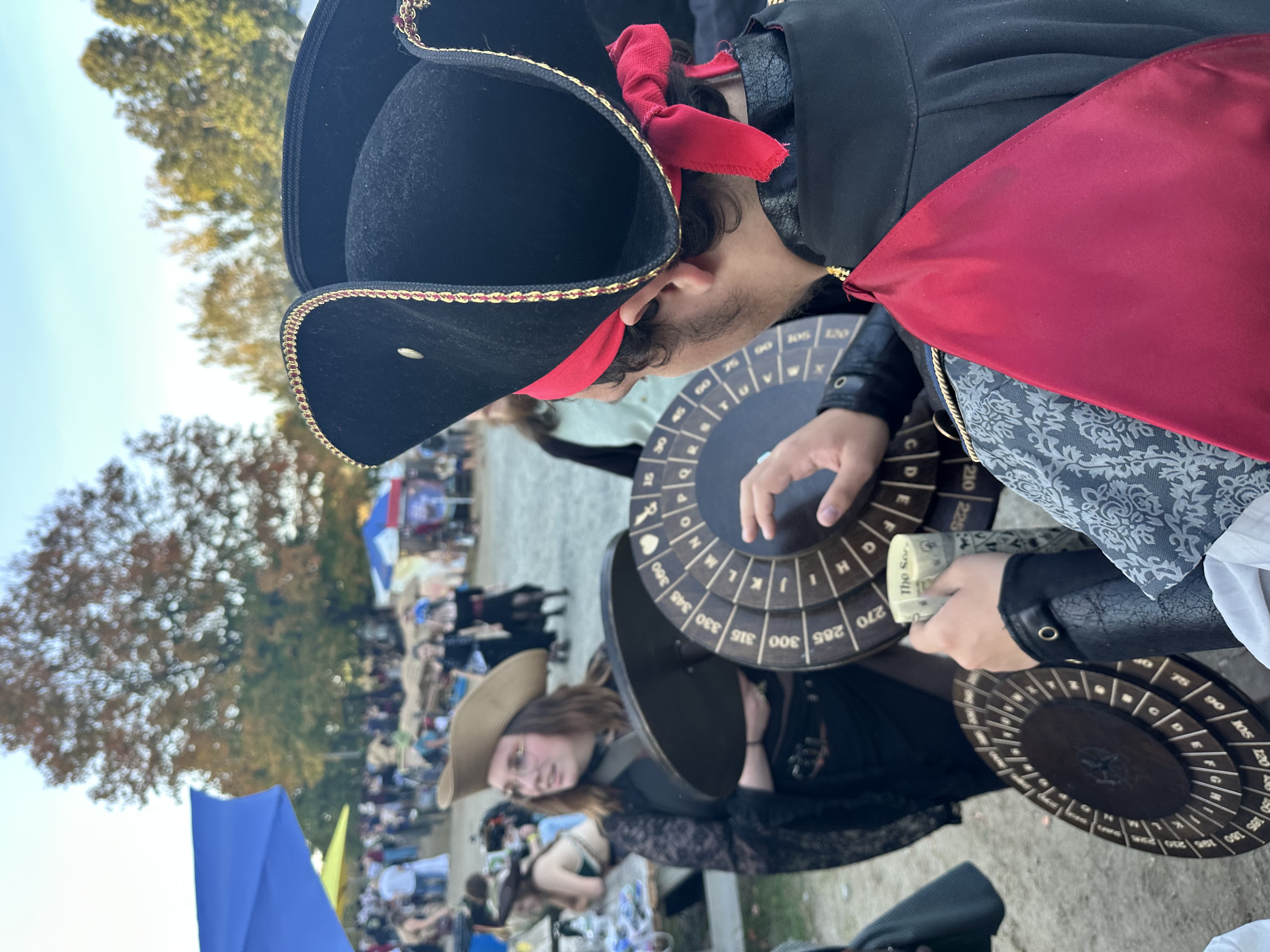 Participant in gold-trimmed tricorn hat spinning the cipher wheel decoder