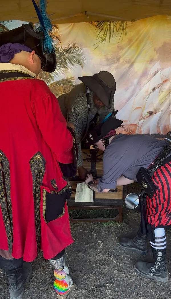 Pirates gathered around a wooden puzzle station inside the treasure tent