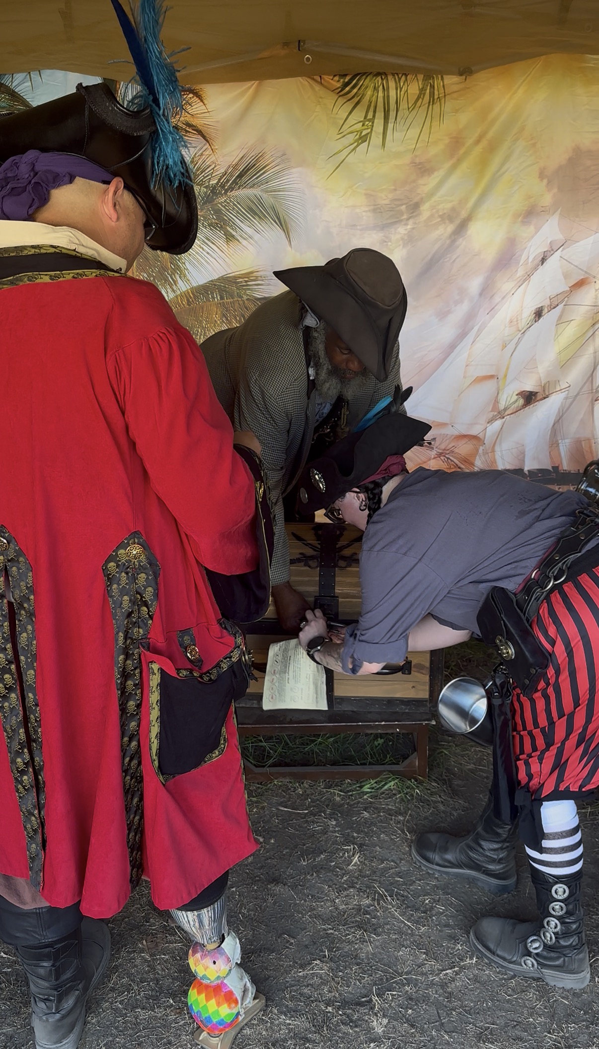 Pirates gathered around a wooden puzzle station inside the treasure tent