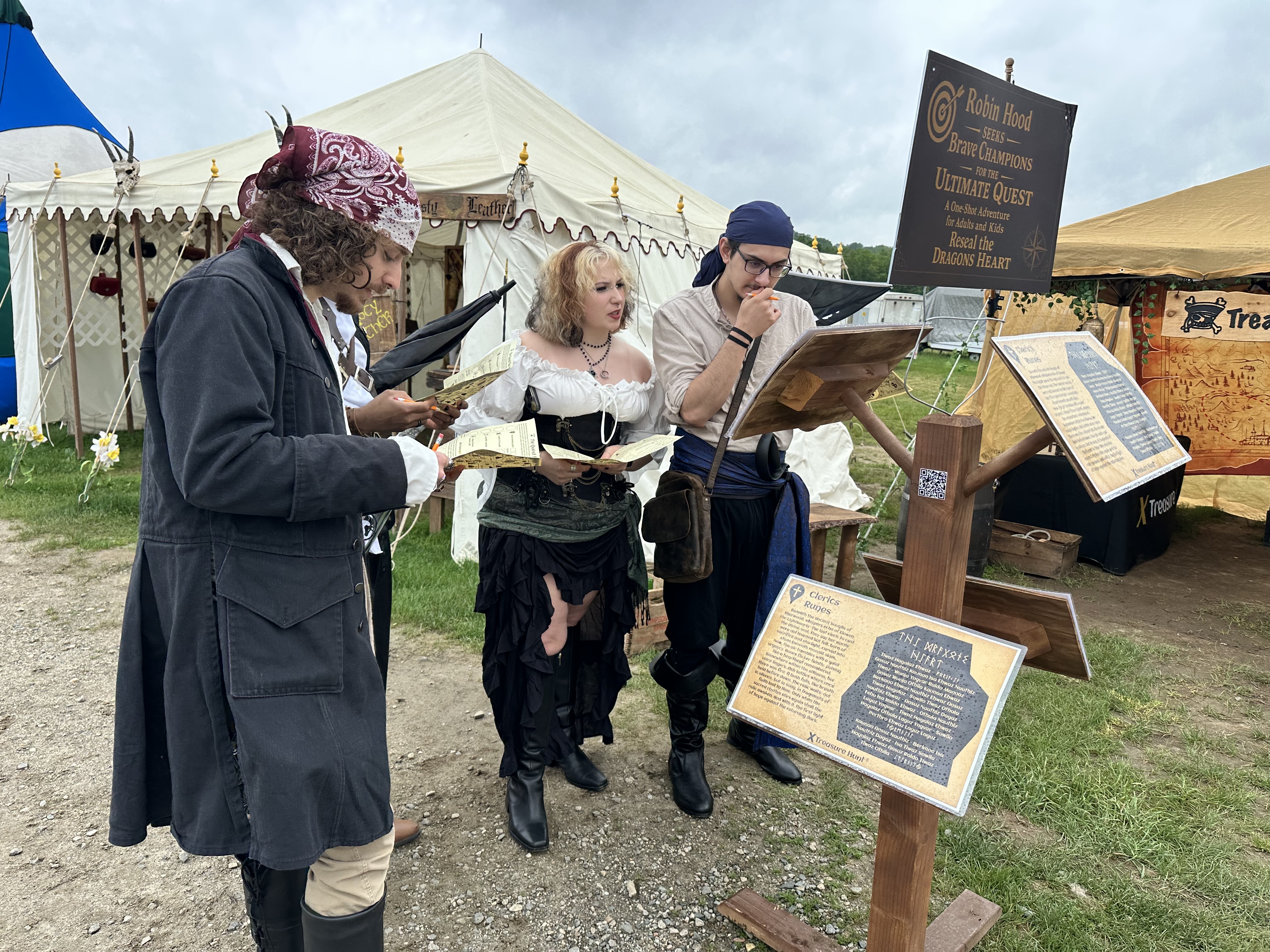 Participants in pirate costumes reading quest clue booklets at Robin Hood's Medieval Faire
