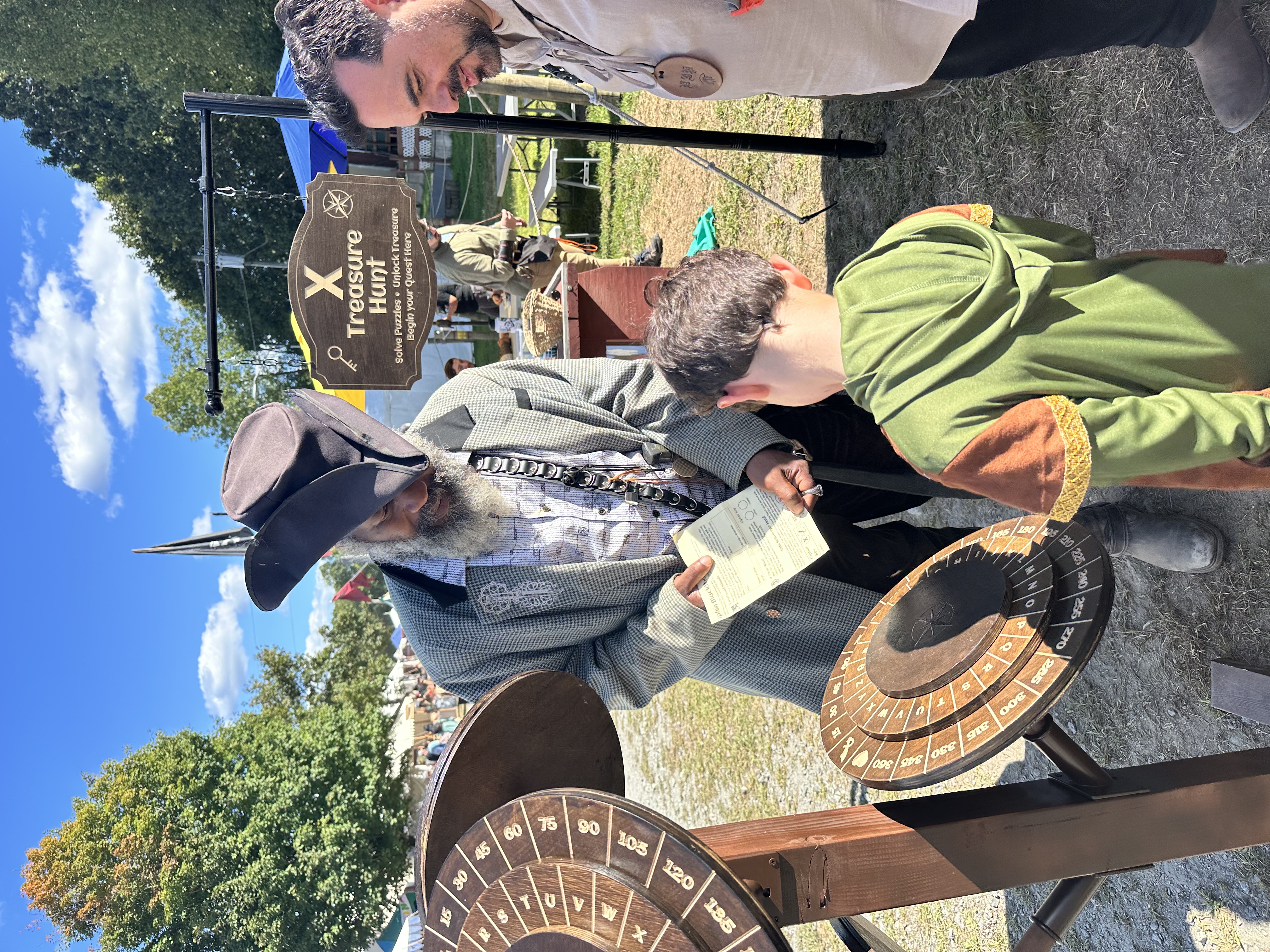 Pirate host showing a quest sheet to a young boy in a Robin Hood tunic
