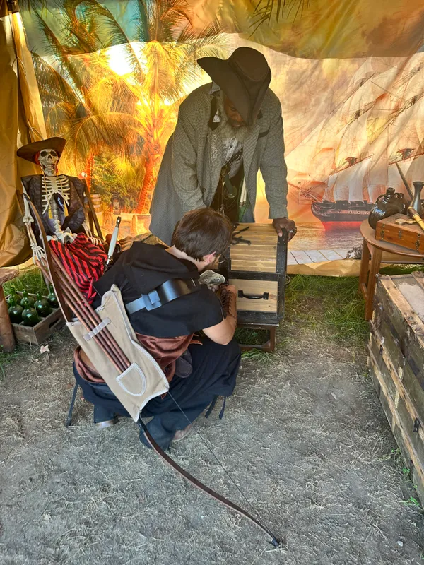 Young archer in Renaissance garb examining the treasure chest contents