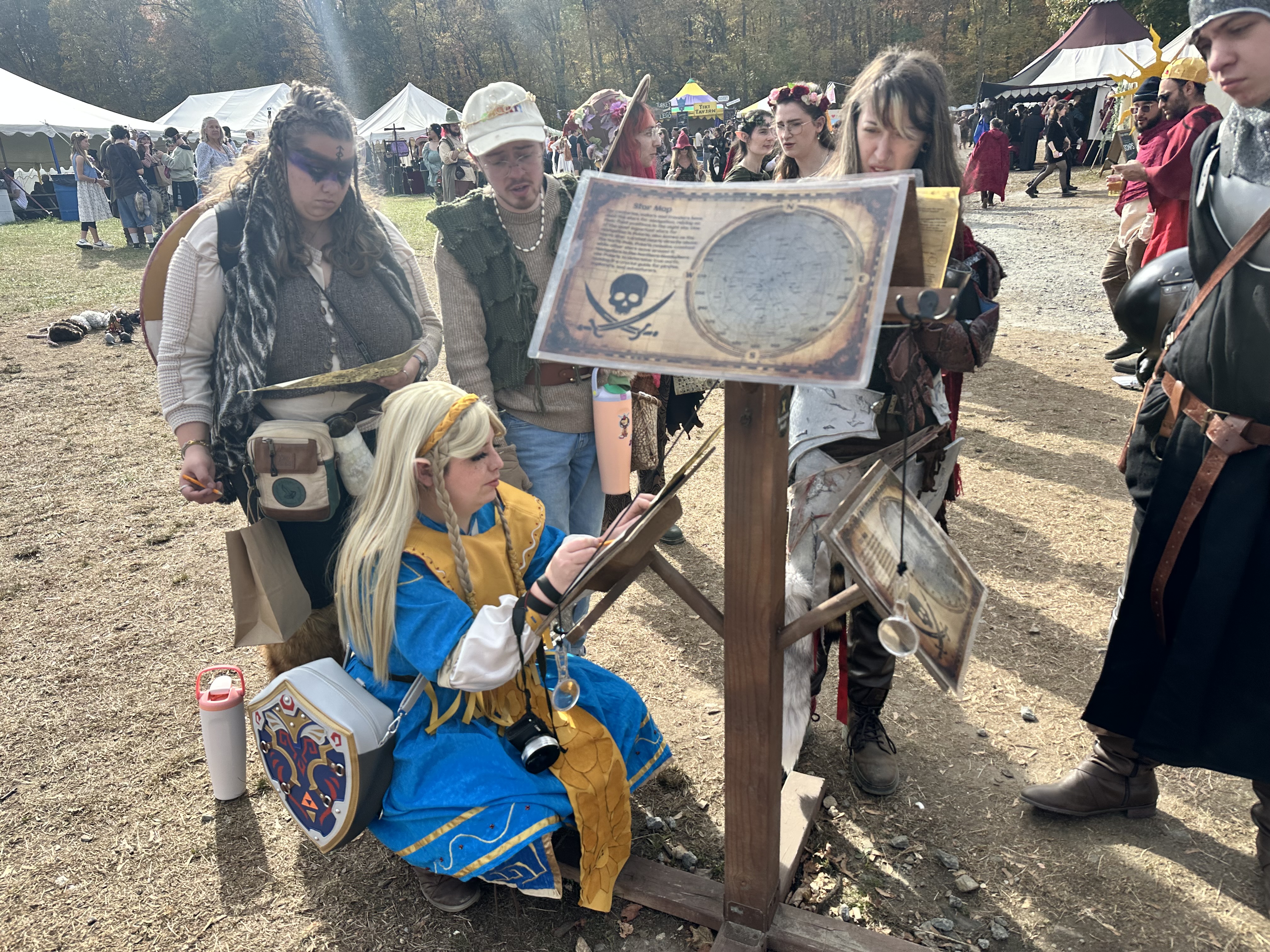 Princess Zelda cosplayer studying pirate star map clues at the faire